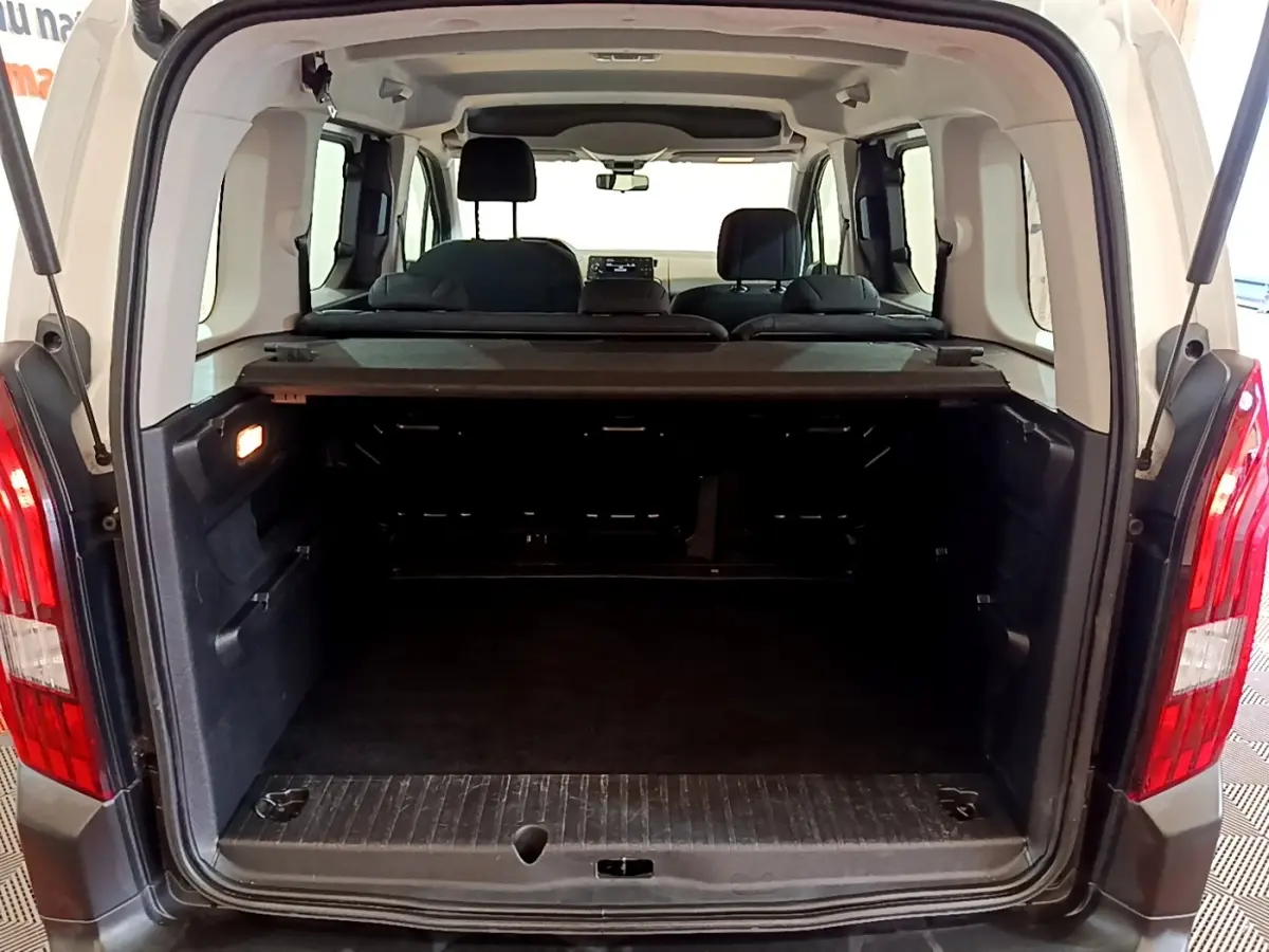 Vue arrière ouverte du coffre spacieux du Peugeot Rifter blanc 2019, avec banquette arrière et tablette cache-bagages visibles.