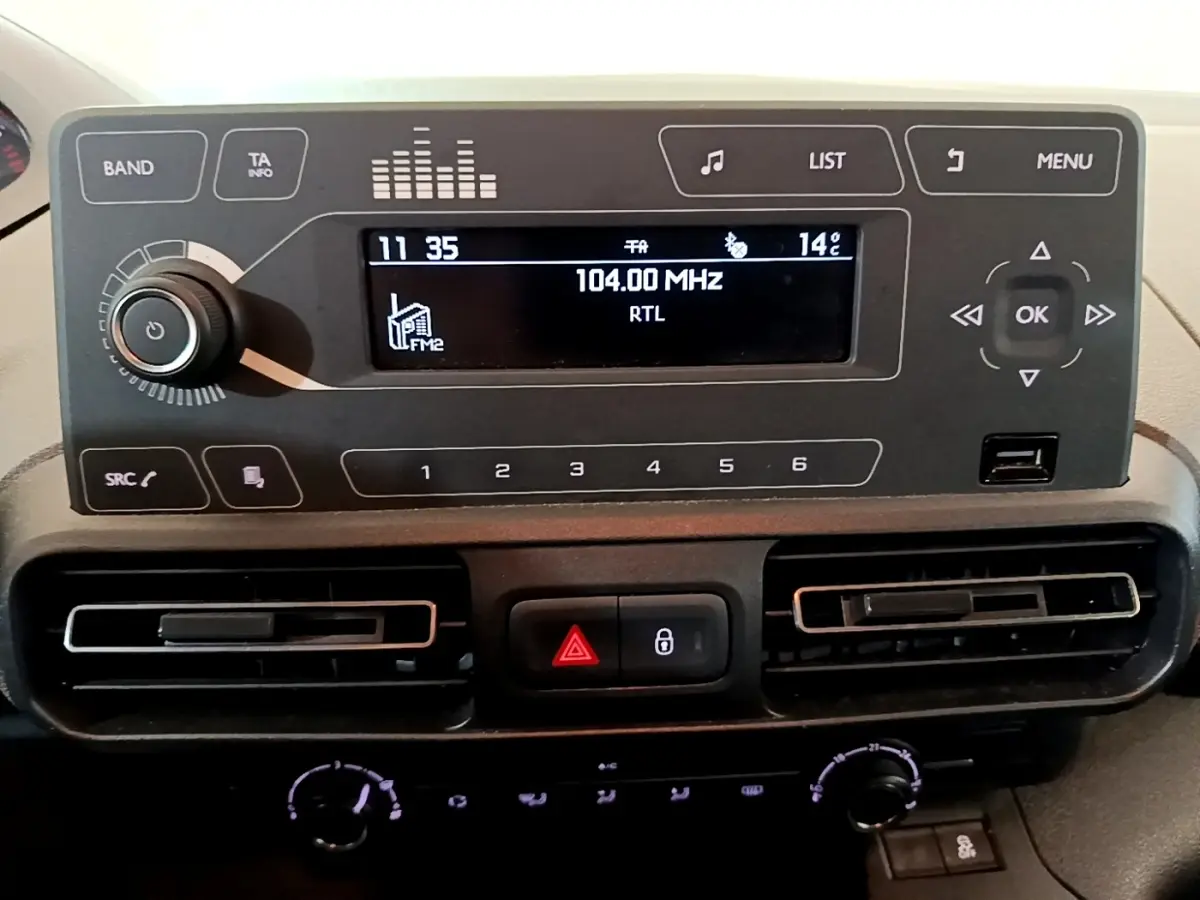 Détail du tableau de bord du Peugeot Rifter 2019 avec écran radio, commandes et aérateurs noirs horizontaux.