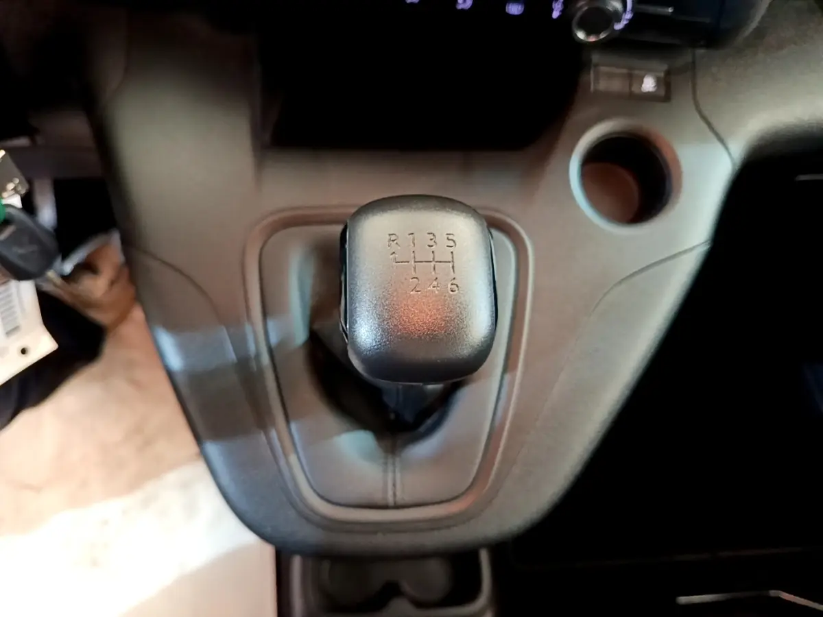 Le levier de vitesses manuel noir en gros plan dans l'habitacle du Peugeot Rifter blanc, vue centrée dessus.