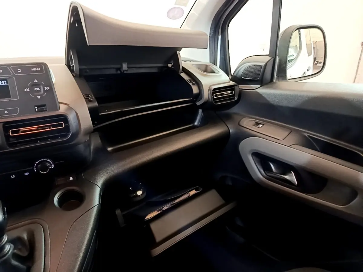 Intérieur côté passager du Peugeot Rifter blanc 2019, avec boîte à gants ouverte et tableau de bord visible.