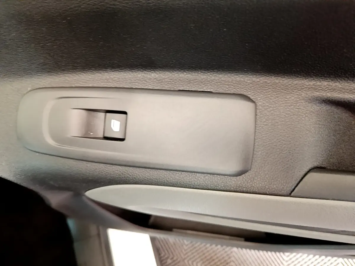 Gros plan sur le bouton de commande de lève-vitre côté gauche intérieur d’un Peugeot Rifter blanc 2019.