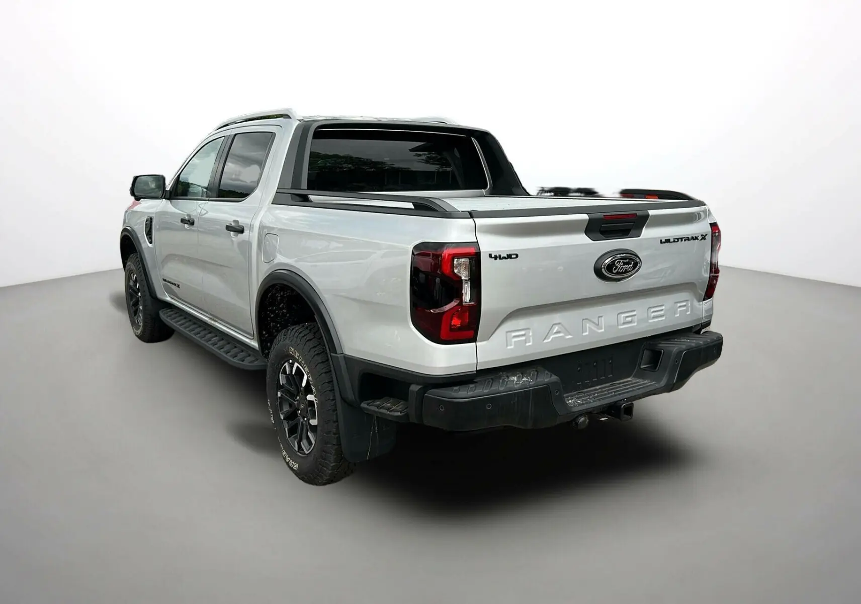 Vue 3/4 arrière droite du Ford Ranger 2025 gris iconic avec arceau sport, jantes noires et ridelles de benne.