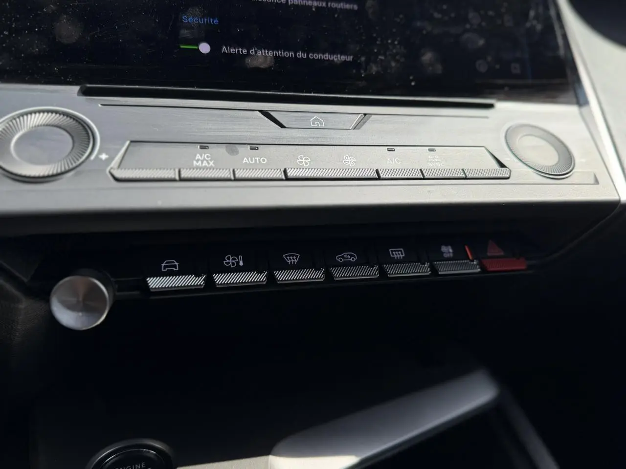 Gros plan sur la console centrale de la Peugeot 308 SW 2025, montrant les commandes climatisation et fonctions assistées.