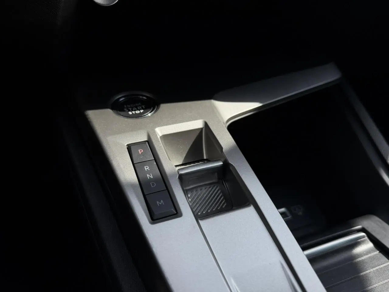 Gros plan sur la console centrale argentée du Peugeot 308 SW 2025 avec boutons de boîte auto et bouton start/stop.