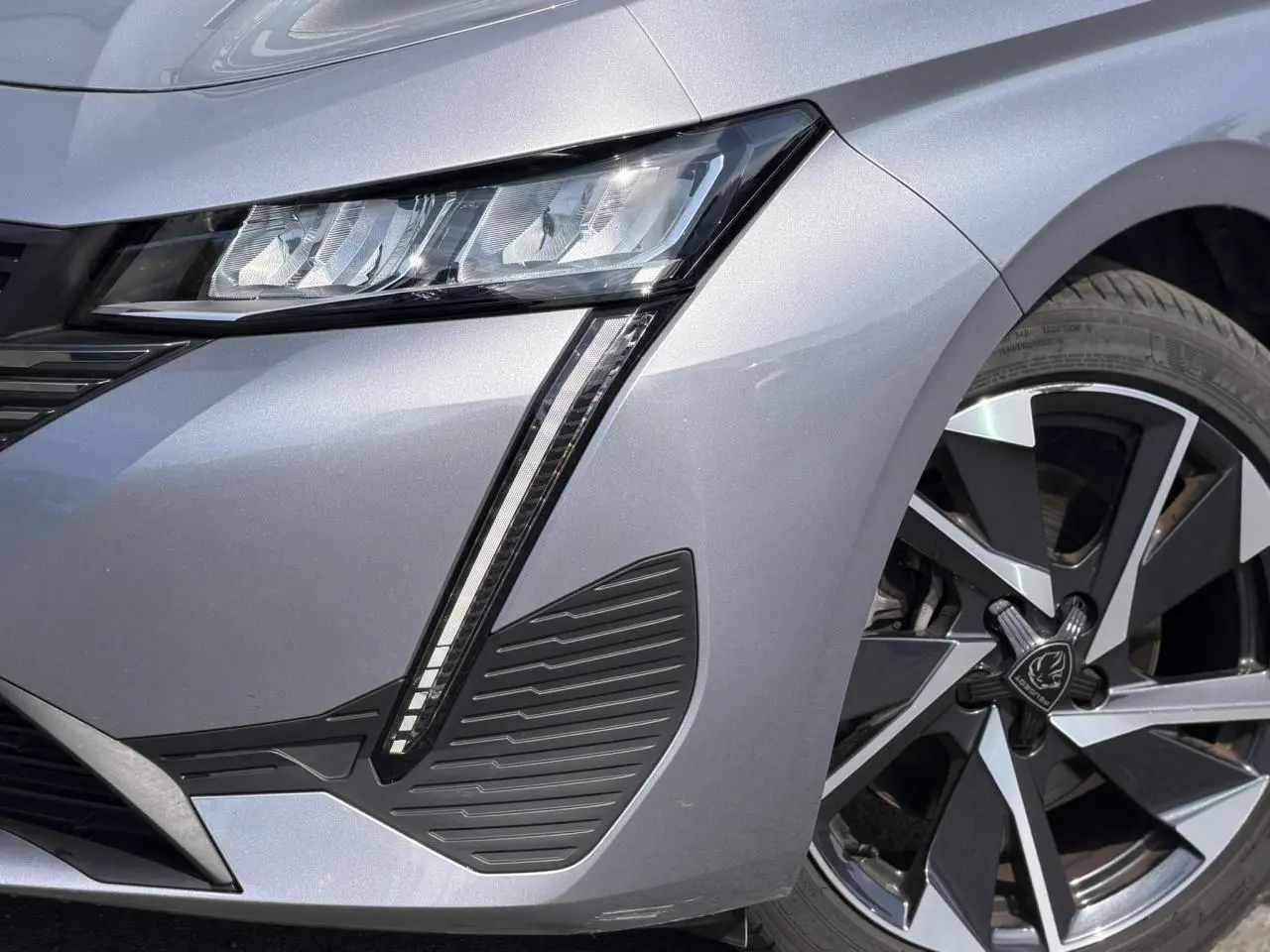 Gros plan sur l’avant droit gris Artense du Peugeot 308 SW 2025, mettant en valeur le phare LED et la jante alliage 17 pouces.