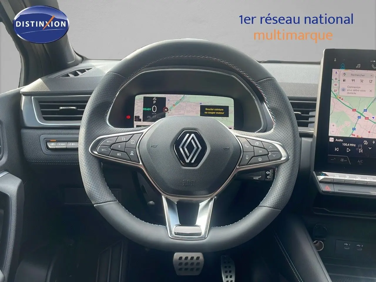 Volant en cuir perforé avec logo Renault au centre, tableau de bord numérique et écran tactile du Renault Captur hybride 2025.