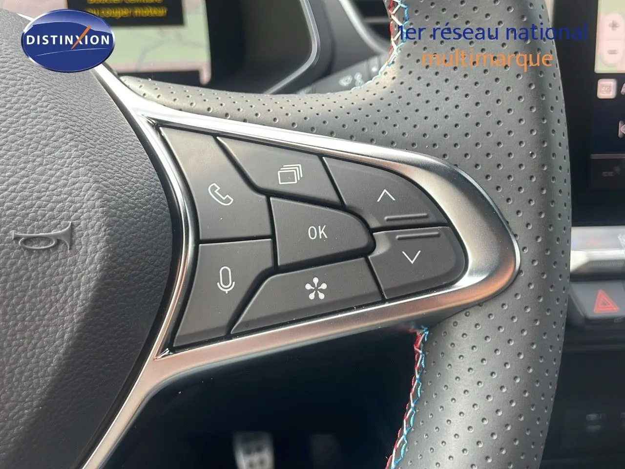 Gros plan sur les commandes multifonctions au volant en cuir perforé noir du Renault Captur E-Tech hybride 2025.