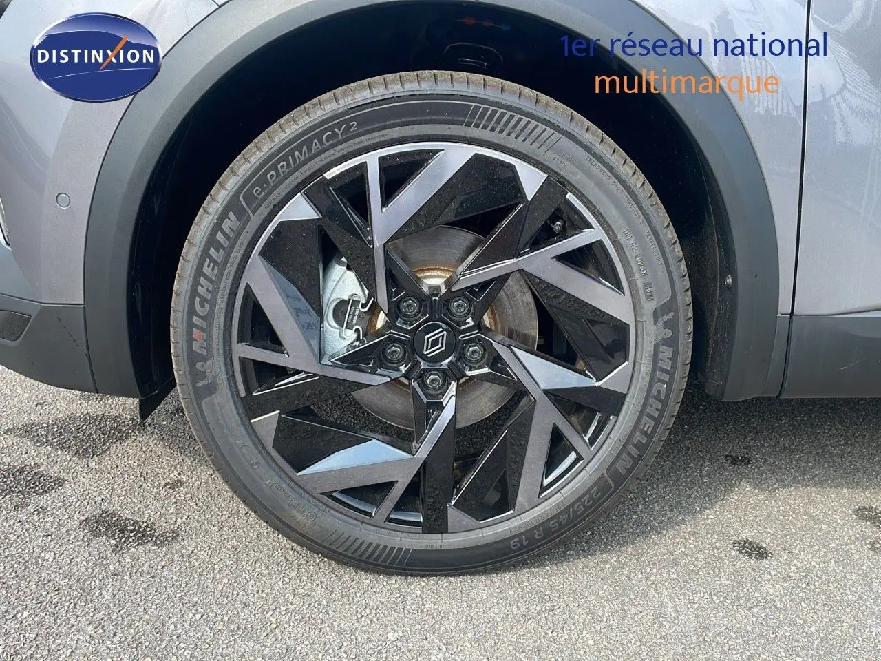 Gros plan sur la roue avant gauche du Renault Captur gris Cassiopée avec jante noire au design géométrique.