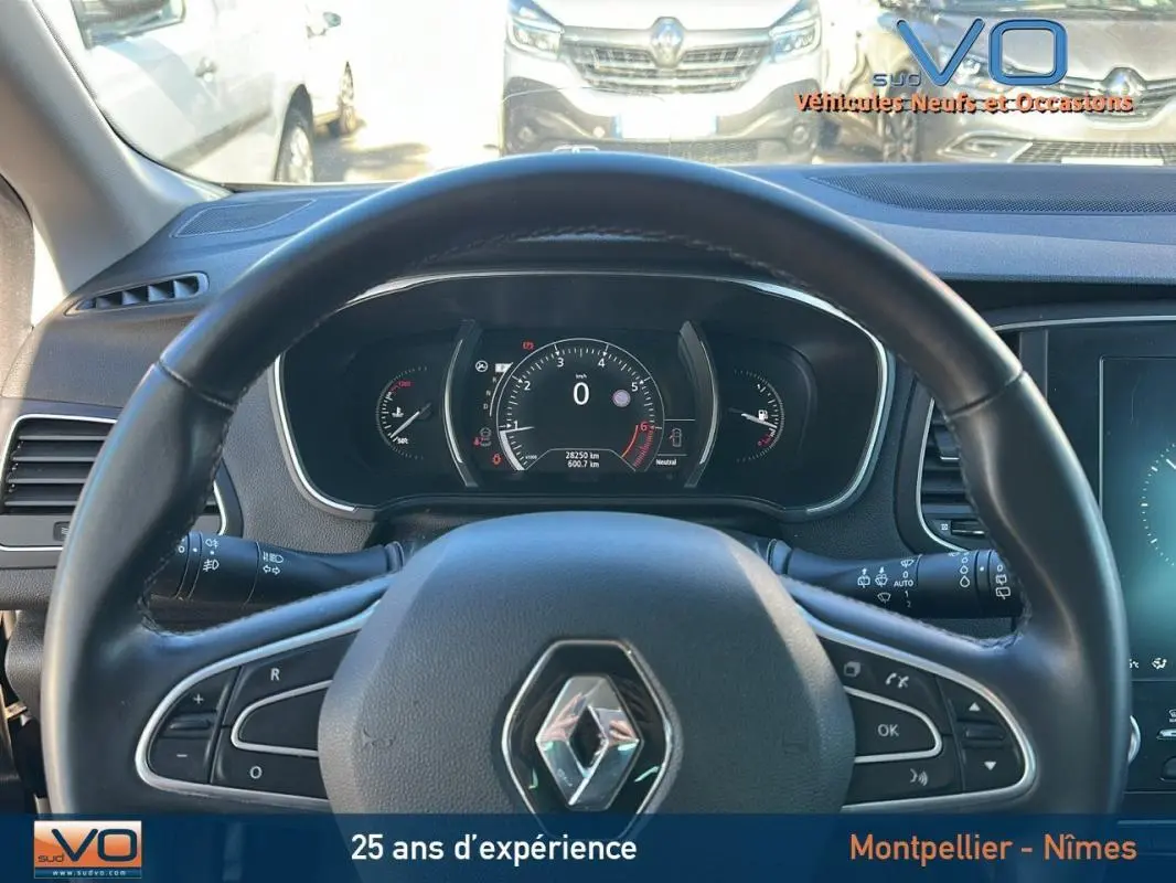 Vue depuis le siège conducteur sur le volant cuir et le tableau de bord numérique d'une Renault Mégane IV beige de 2017.