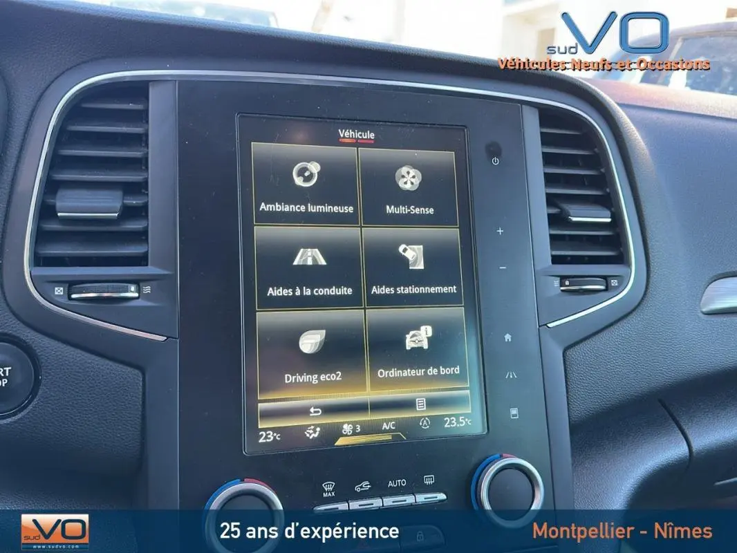 Écran tactile central de la Renault Mégane IV beige, affichant les aides à la conduite et climatisation automatique.