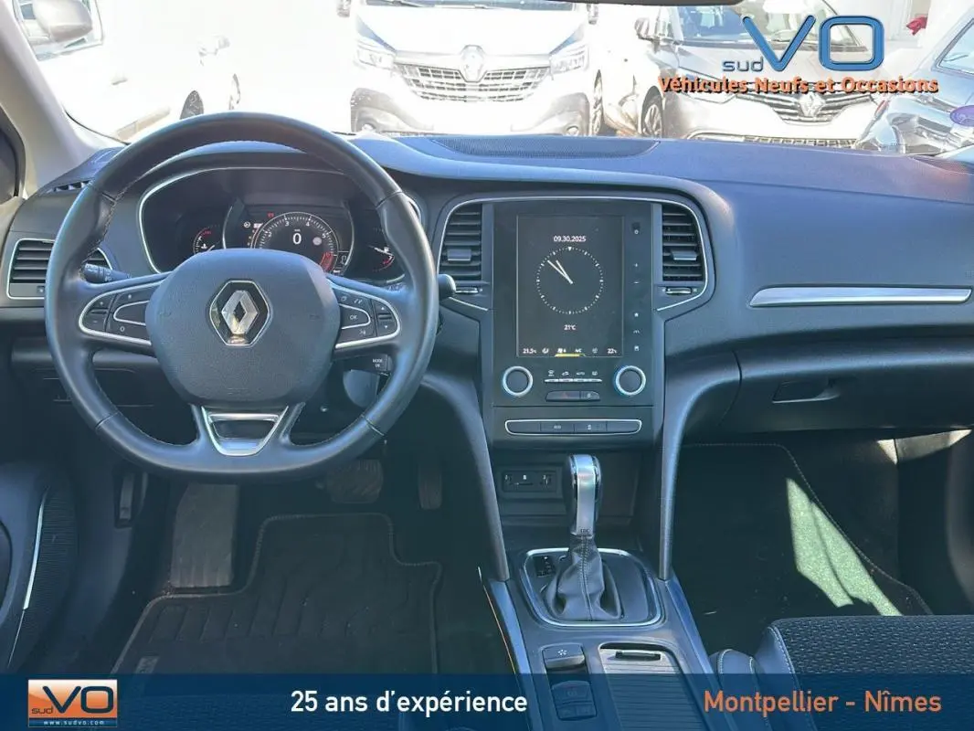 Tableau de bord et volant cuir d'une Renault Mégane IV beige, avec écran tactile et levier de boîte automatique visible.