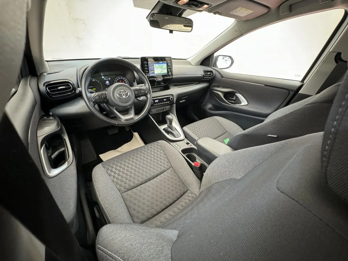 Vue intérieure avant droite de la Toyota Yaris hybride 2022, montrant le tableau de bord avec écran tactile et volant multifonctions.