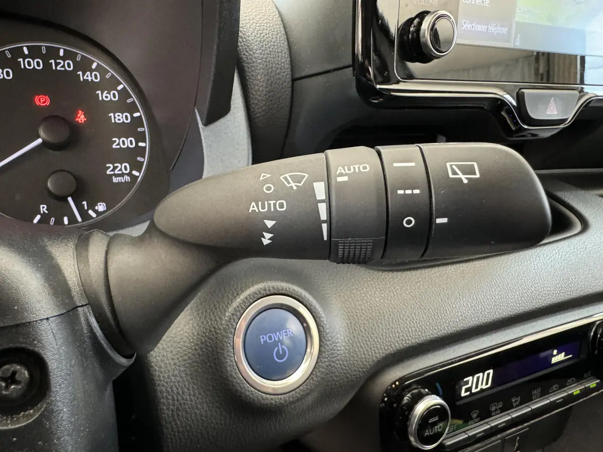 Gros plan sur la commande d’essuie-glace et bouton Power du tableau de bord noir de la Toyota Yaris hybride 2022.