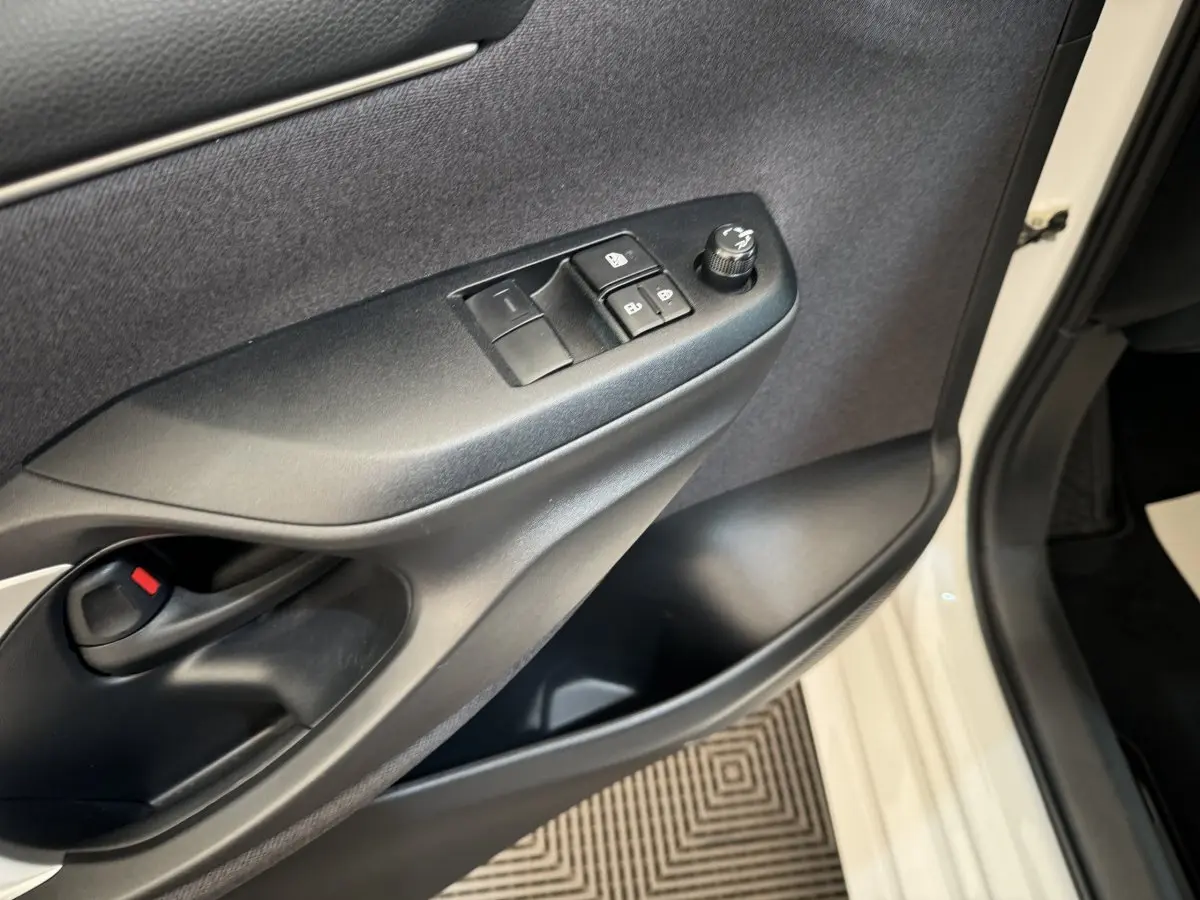 Gros plan sur la porte avant gauche blanche d'une Toyota Yaris hybride, montrant les commandes de vitres et rétroviseurs.