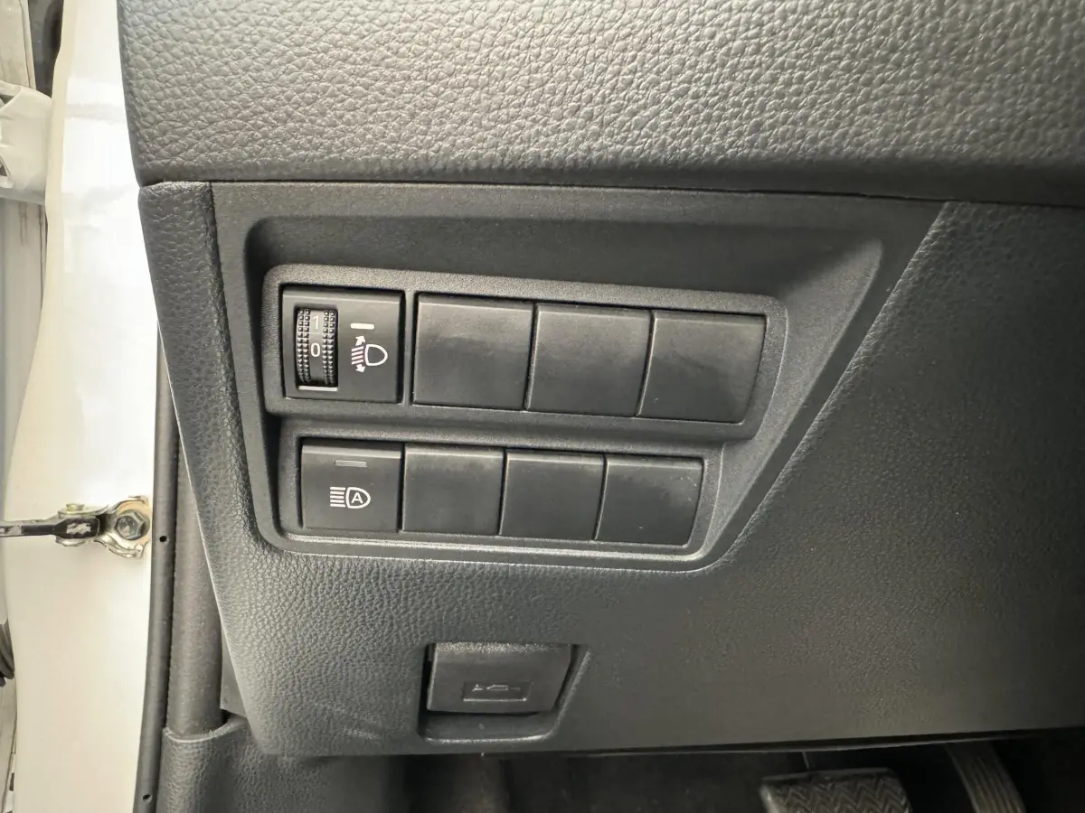 Panneau de commandes côté conducteur de la Toyota Yaris blanche 2022 avec réglage phares et assistant feux automatiques.