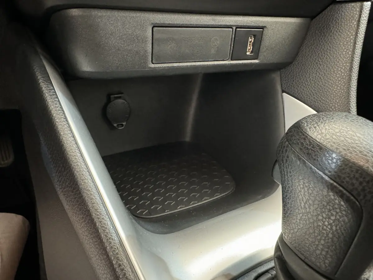 Gros plan sur la console centrale noire et grise de la Toyota Yaris hybride 2022, avec prise USB et levier de vitesse cuir.