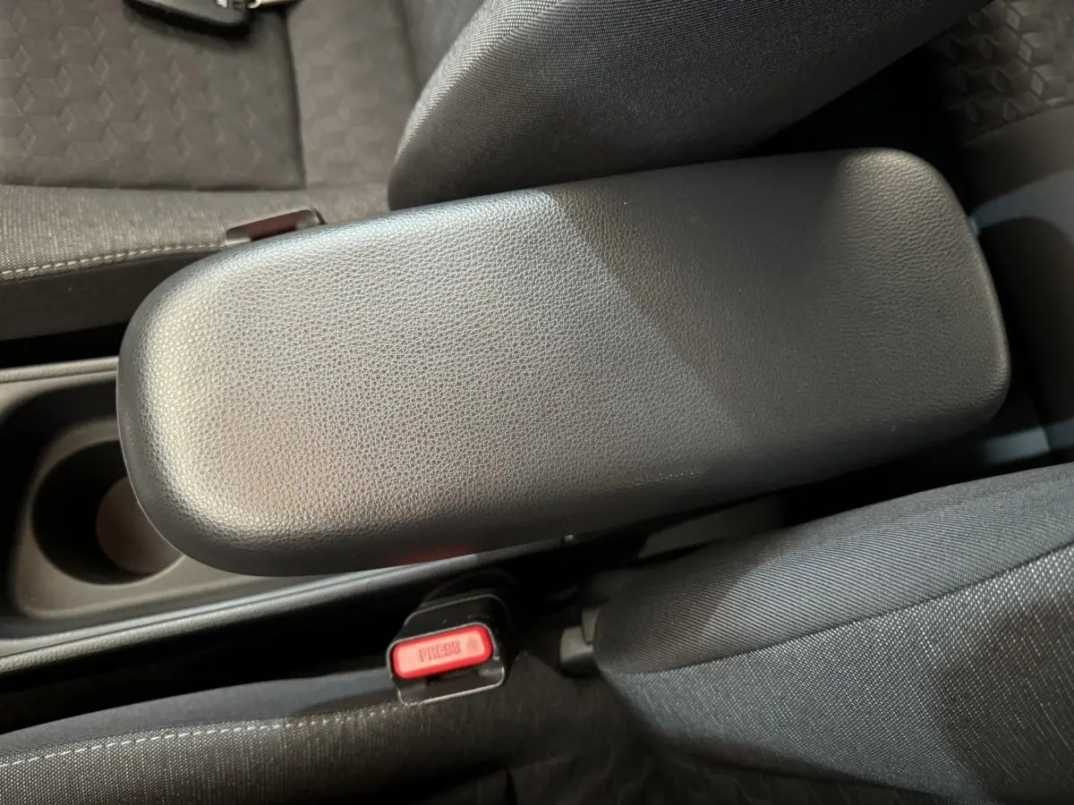 Accoudoir central noir en cuir avec bouton de ceinture rouge, intérieur tissu gris de Toyota Yaris hybride 2022.