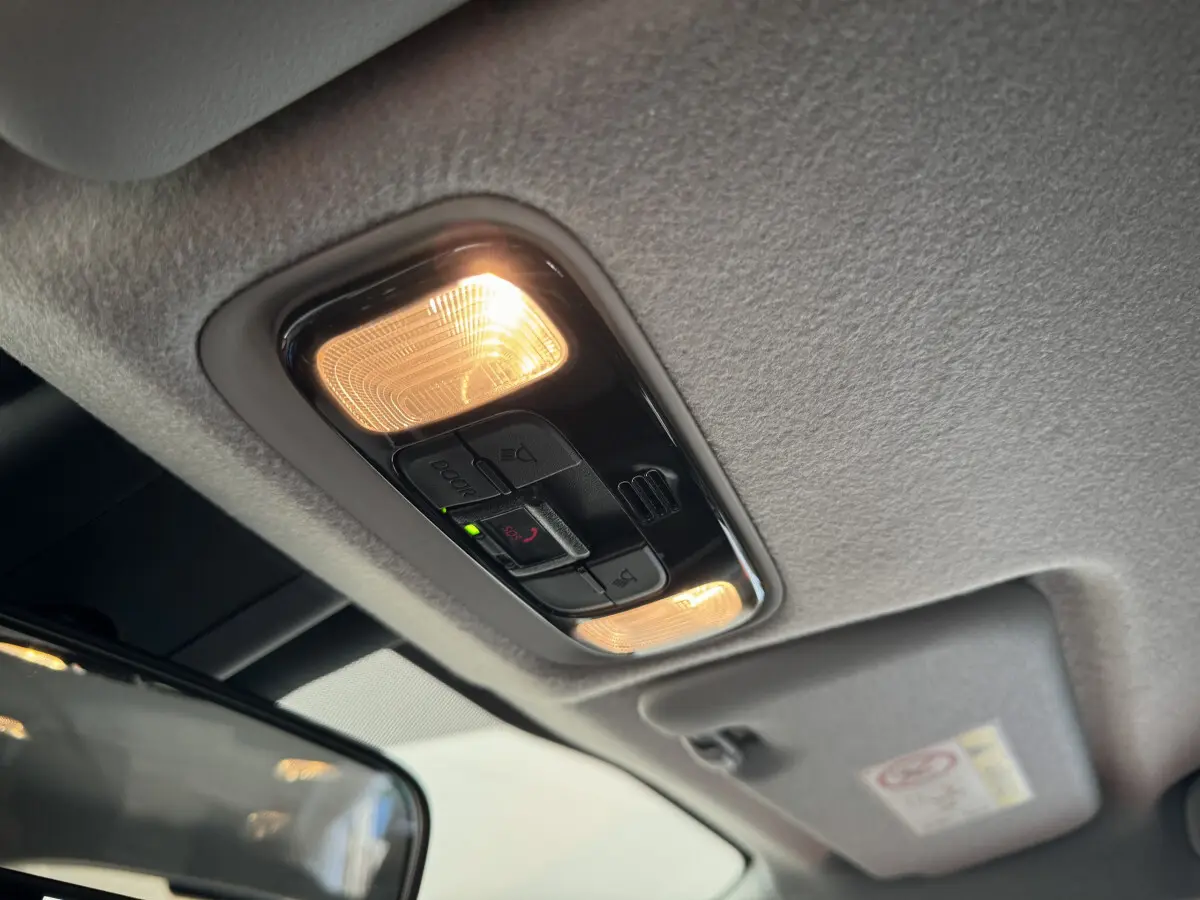 Plafonnier intérieur allumé avec commandes d’éclairage et bouton SOS dans une Toyota Yaris blanche hybride 2022.