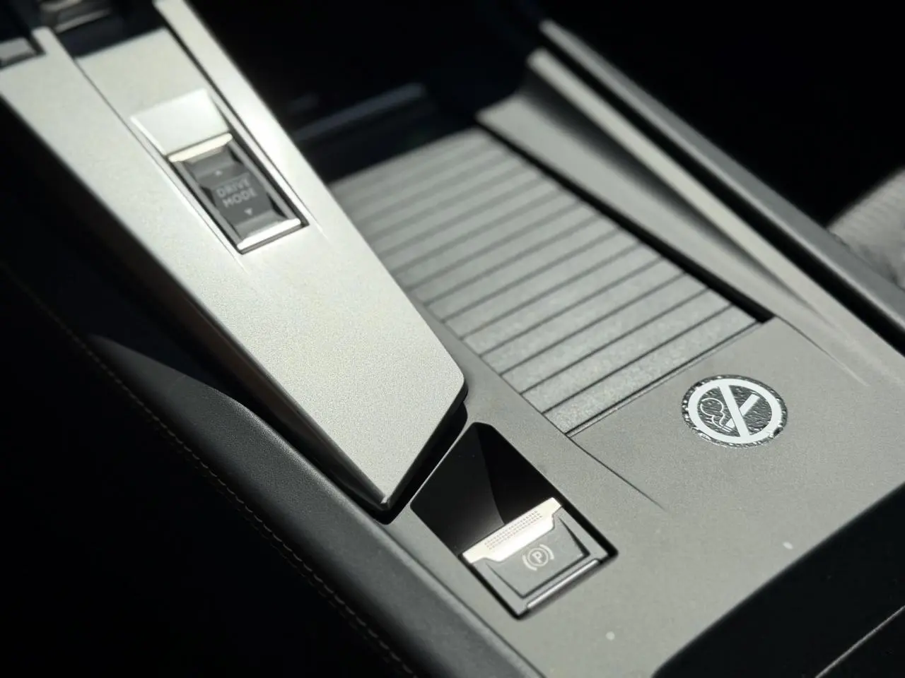 Gros plan sur la console centrale noire avec bouton Drive Mode et frein de parking électrique du Peugeot 308 SW 2024.