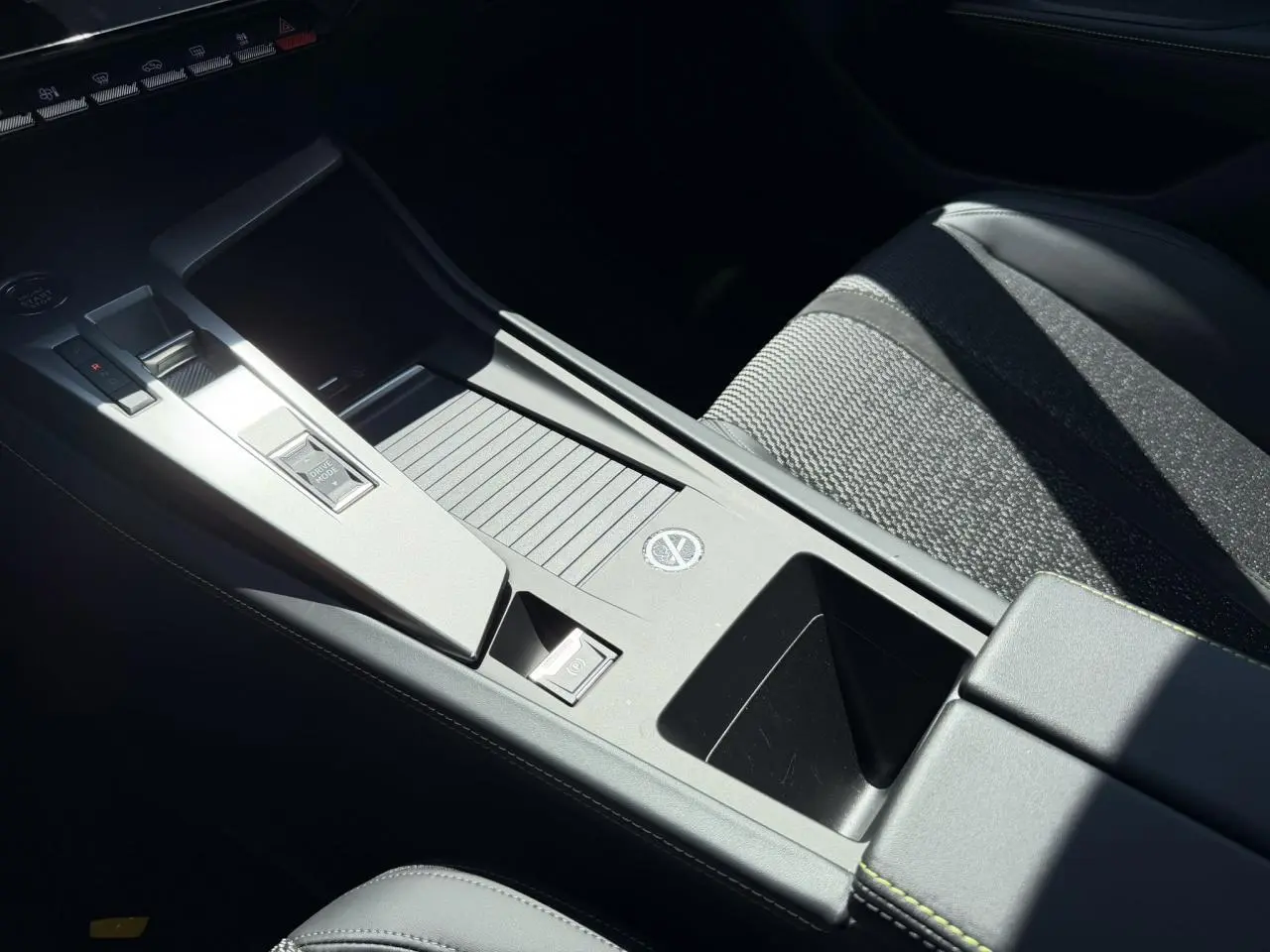 Gros plan sur la console centrale grise et siège tissu noir de la Peugeot 308 SW 2024, intérieur moderne et épuré.