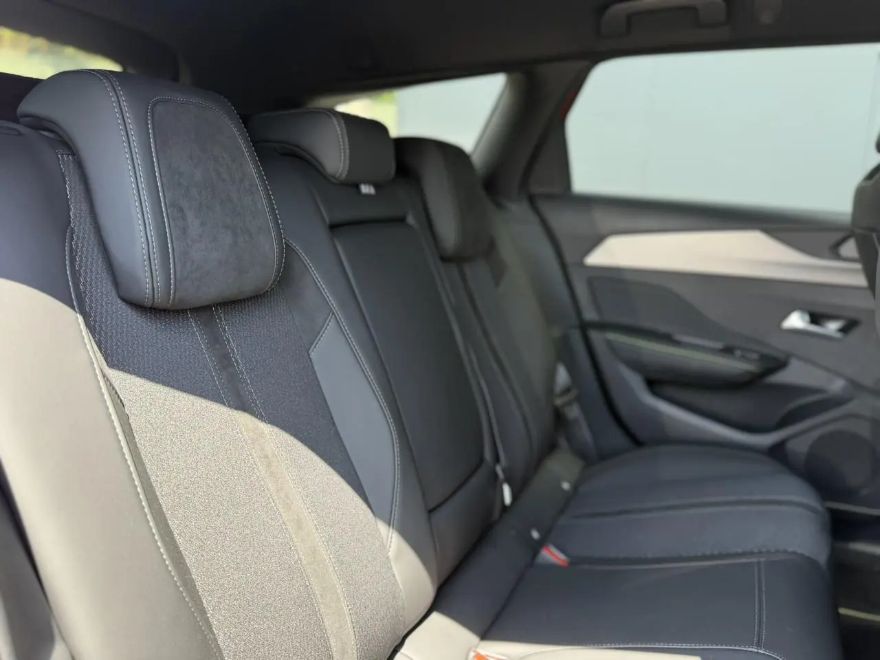 Vue latérale droite des sièges arrière en sellerie tri matières noire de la Peugeot 308 SW 2024.