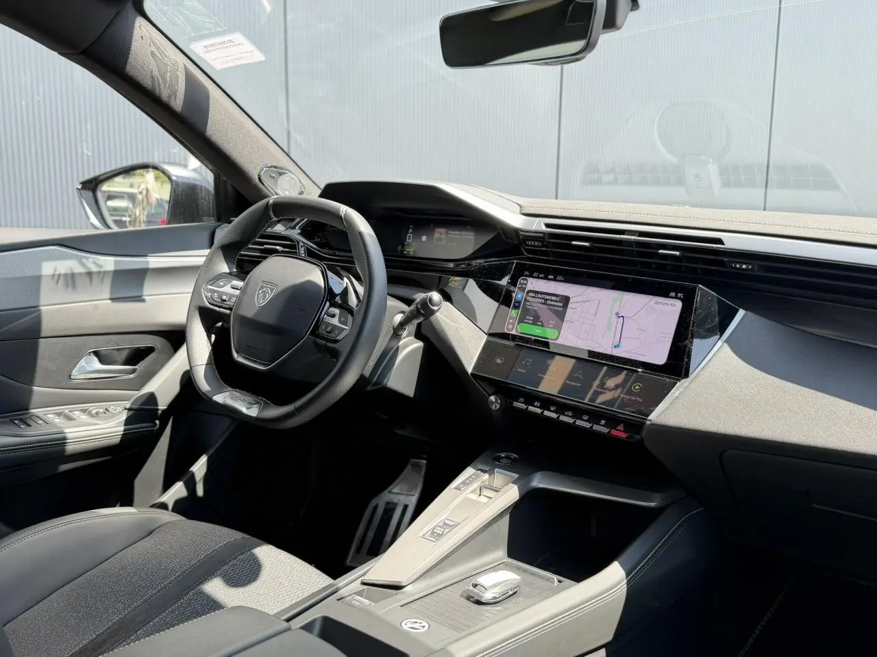 Vue intérieure côté conducteur du Peugeot 308 SW 2024, mettant en valeur le tableau de bord numérique et l’écran tactile central.