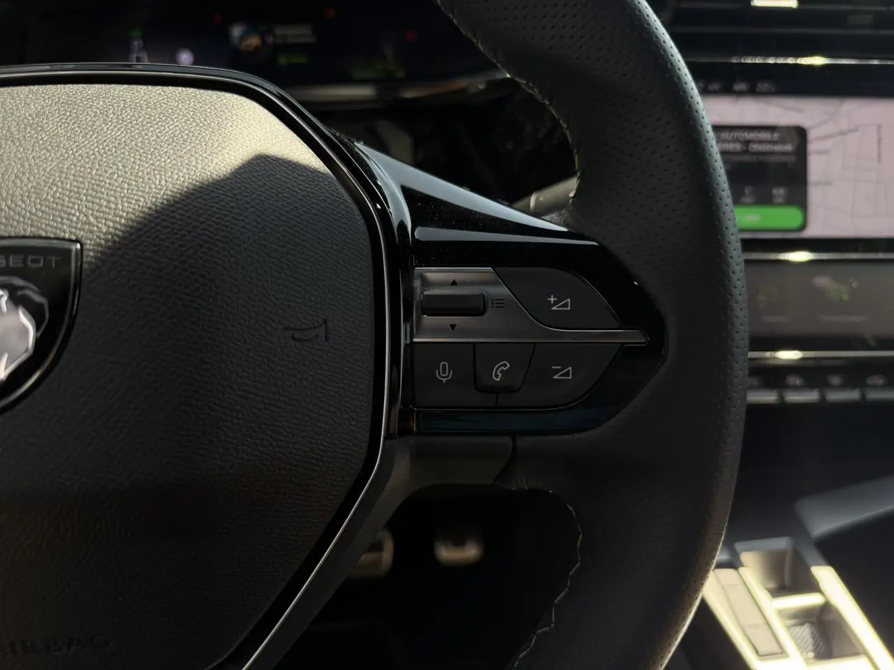 Gros plan sur les commandes à droite du volant cuir perforé de la Peugeot 308 SW 2024, intérieur noir.
