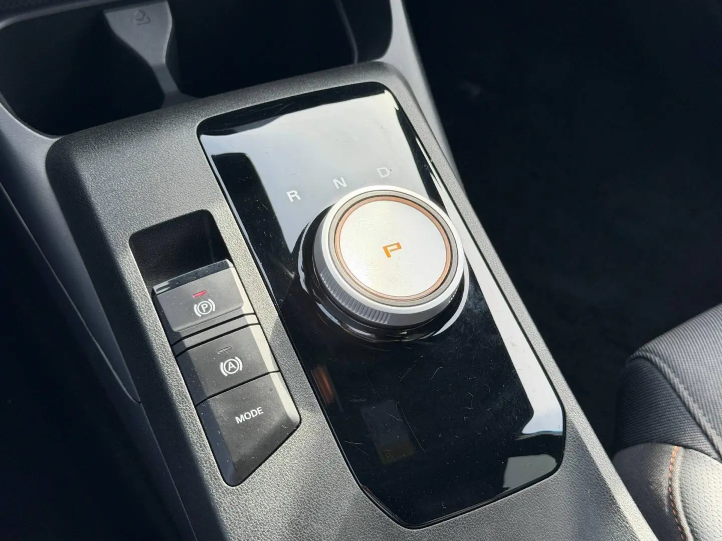 Gros plan sur la console centrale noire brillante avec sélecteur rotatif de boîte auto et boutons mode et frein à main MG3 2025.
