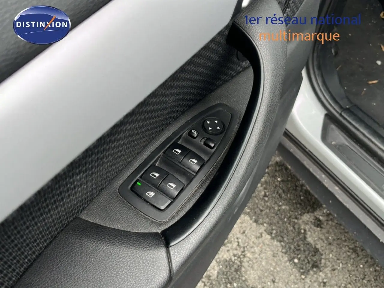 Détail des commandes des vitres sur la porte avant gauche d’un BMW X1 gris argent 2018.