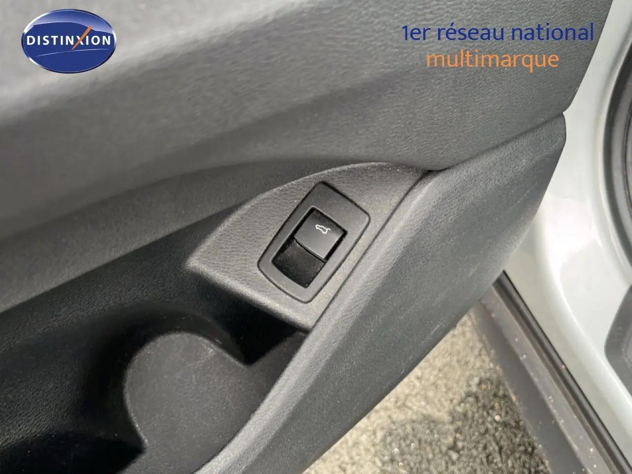 Gros plan sur le bouton d'ouverture du coffre intégré à la portière côté gauche d'une BMW X1 gris argent 2018.