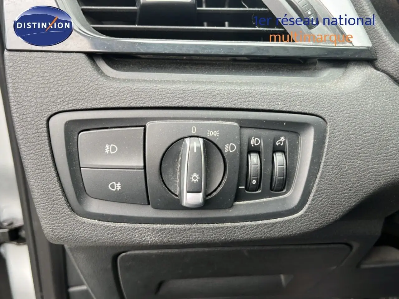 Gros plan sur les commandes d’éclairage intérieures du BMW X1 18i gris argent, avec boutons et molette de réglage.