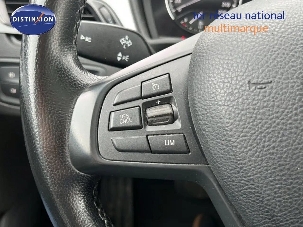 Gros plan sur le volant côté gauche d'une BMW X1 gris argent 2018, avec commandes de régulateur de vitesse.