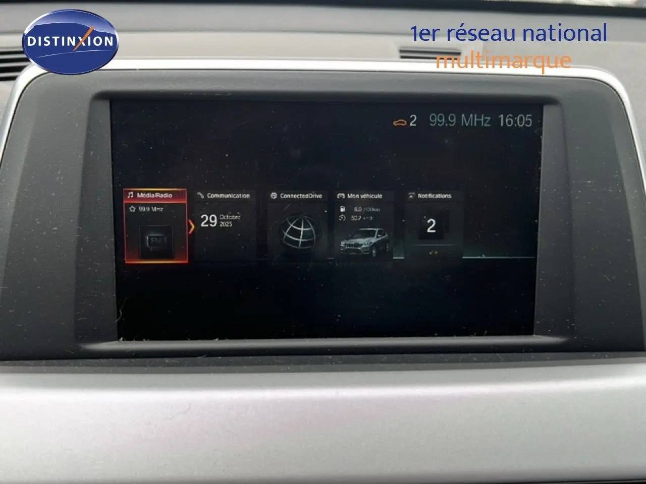 Écran multimédia du tableau de bord du BMW X1 18i gris argent, affichant radio et informations véhicule.