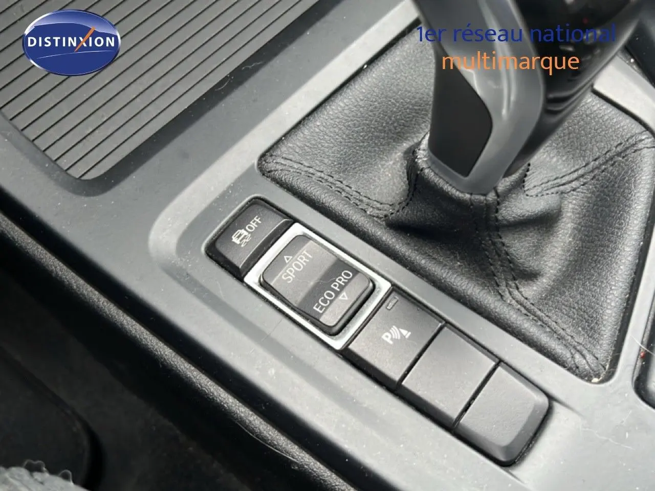 Gros plan sur la console centrale de la BMW X1 18i 2018, montrant le levier de vitesses et les boutons de modes de conduite.