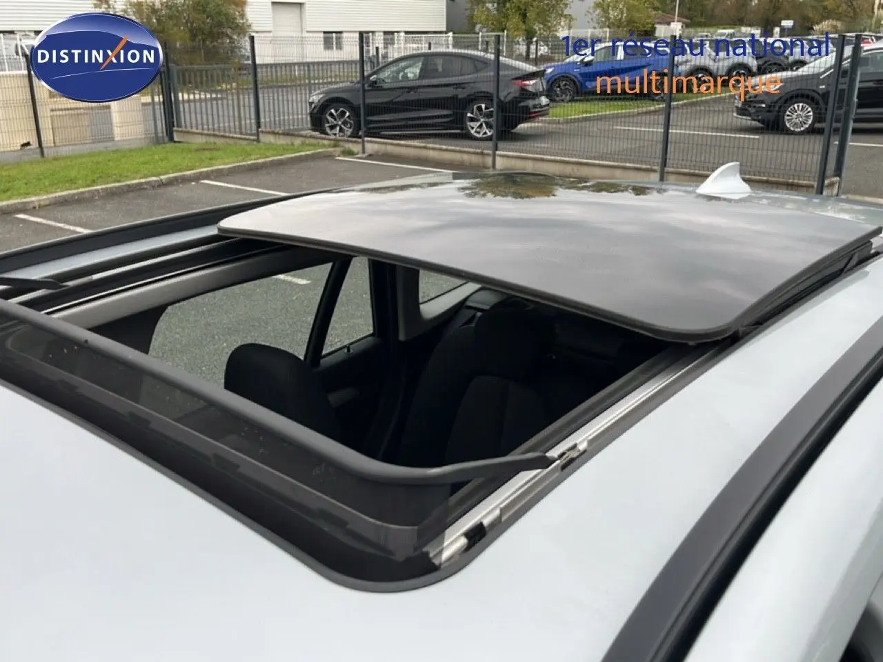 Toit ouvrant panoramique ouvert sur BMW X1 gris argent métal, vue rapprochée depuis le dessus côté gauche.