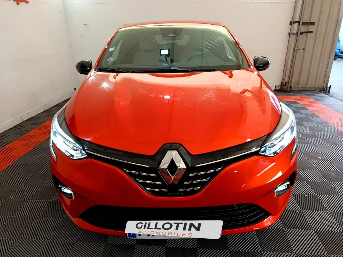 Vue frontale d'une Renault Clio Initiale Paris E-TECH 140 2021 orange avec phares LED et calandre noire brillante.