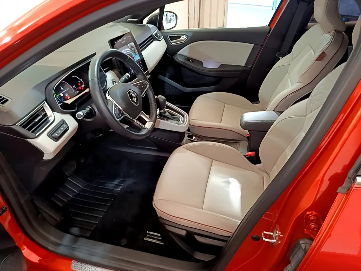Intérieur avant droit d'une Renault Clio Initiale Paris orange 2021, sièges cuir beige et tableau de bord moderne.