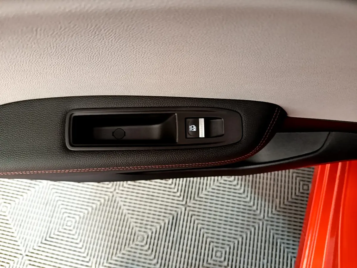 Poignée intérieure côté gauche avec bouton de verrouillage sur porte orange d'une Renault Clio Initiale Paris E-TECH 2021.