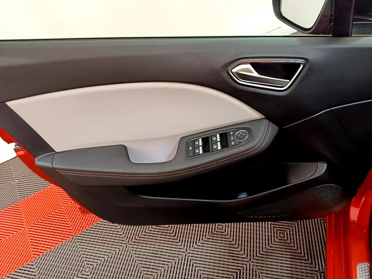 Intérieur côté gauche de la porte d'une Renault Clio orange 2021, avec commandes électriques et garniture bicolore beige et noire.