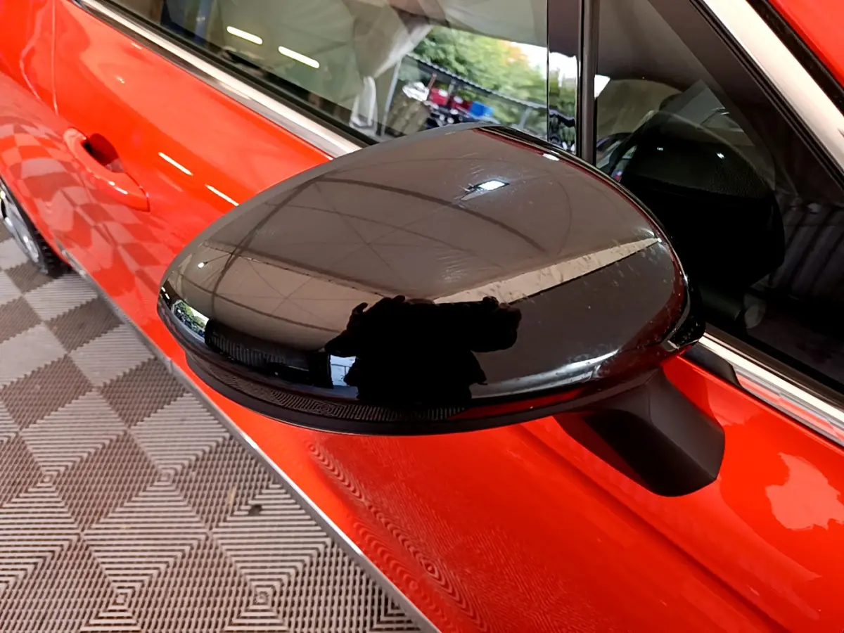 Rétroviseur noir en gros plan côté gauche sur Renault Clio Initiale Paris E-TECH 140 orange vue latérale