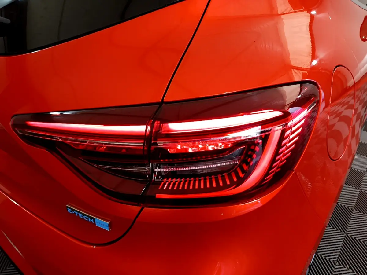 Feu arrière droit allumé sur Renault Clio Initiale Paris E-TECH 140 orange, vue rapprochée du côté arrière droit.