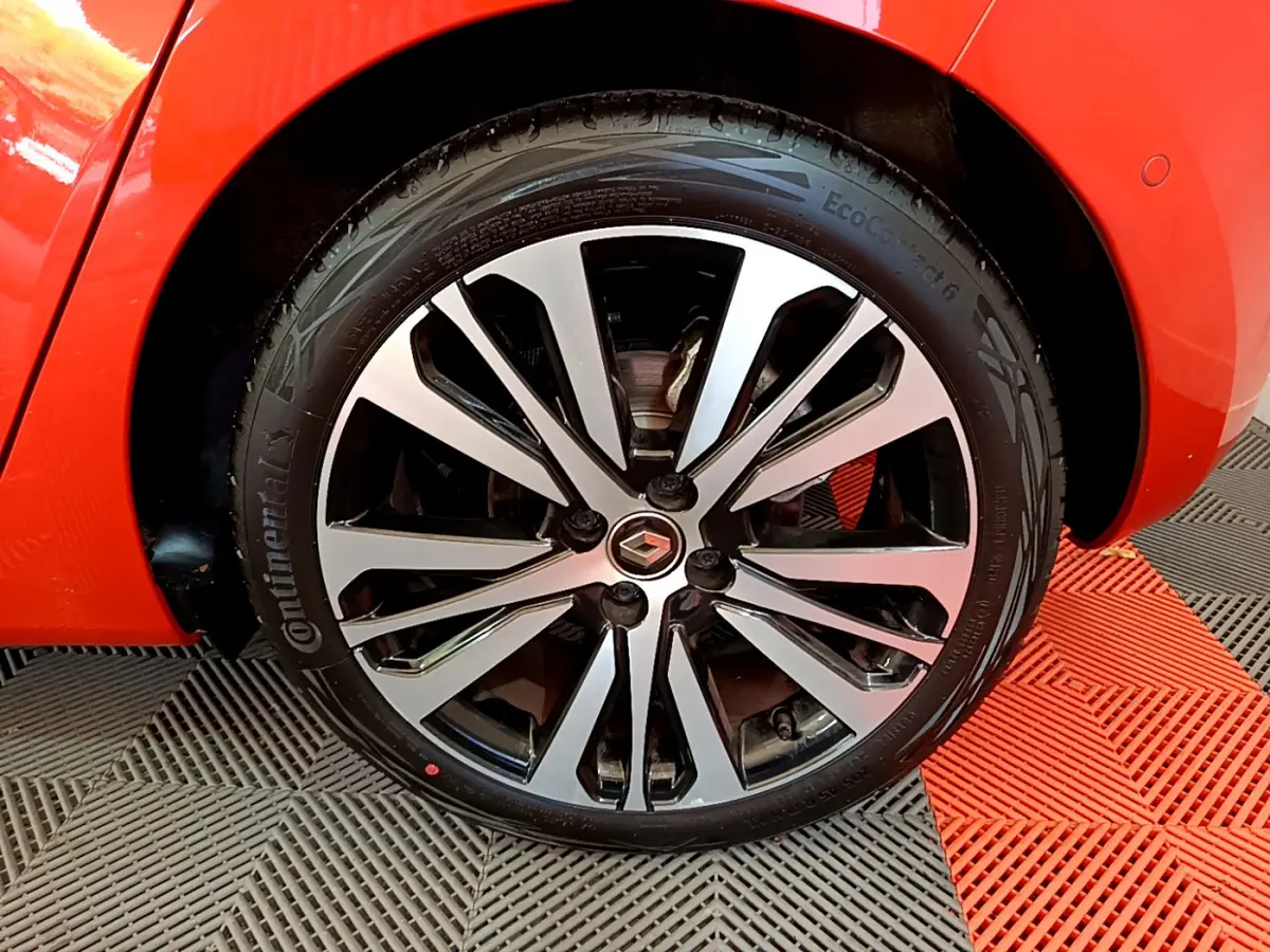 Gros plan sur la roue avant droite de la Renault Clio Initiale Paris orange avec jante alliage bicolore.