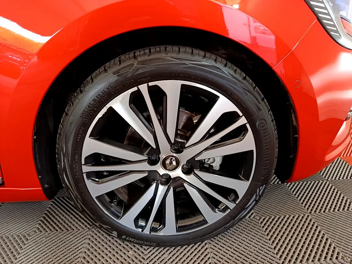 Gros plan sur la roue avant gauche orange d'une Renault Clio Initiale Paris 2021 avec jante alliage noire et argentée.