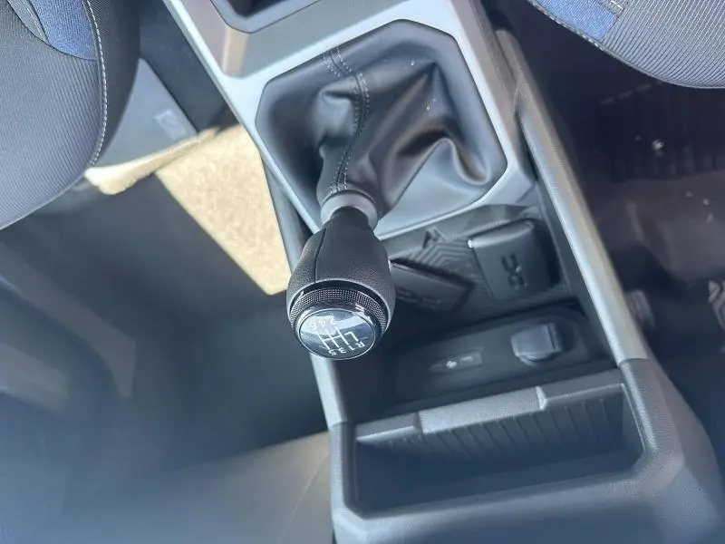 Gros plan sur le levier de vitesses manuel noir du Dacia Duster 2025, avec console centrale et rangements visibles.