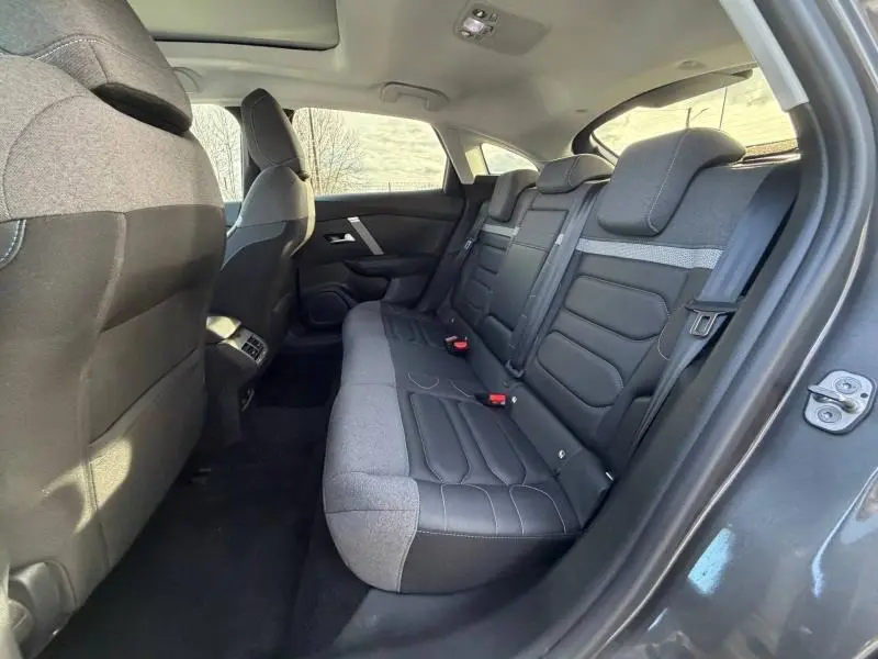Vue intérieure arrière côté droit du Citroën C4 2024 gris, montrant les sièges arrière bicolores en tissu et cuir.