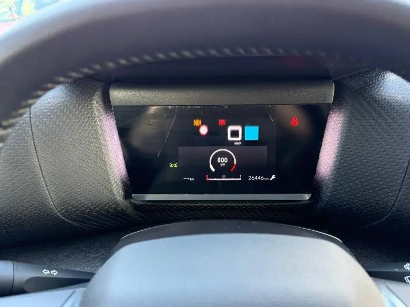 Vue rapprochée du tableau de bord numérique du Citroën C4 2024 gris, affichant le compte-tours et les voyants d'alerte.