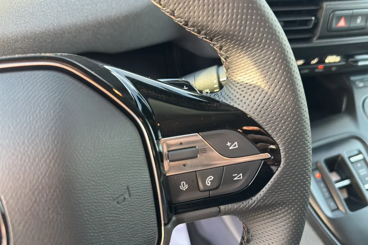 Gros plan sur le volant cuir perforé du Peugeot Rifter GT Plus 2025 avec commandes multifonctions noires brillantes.