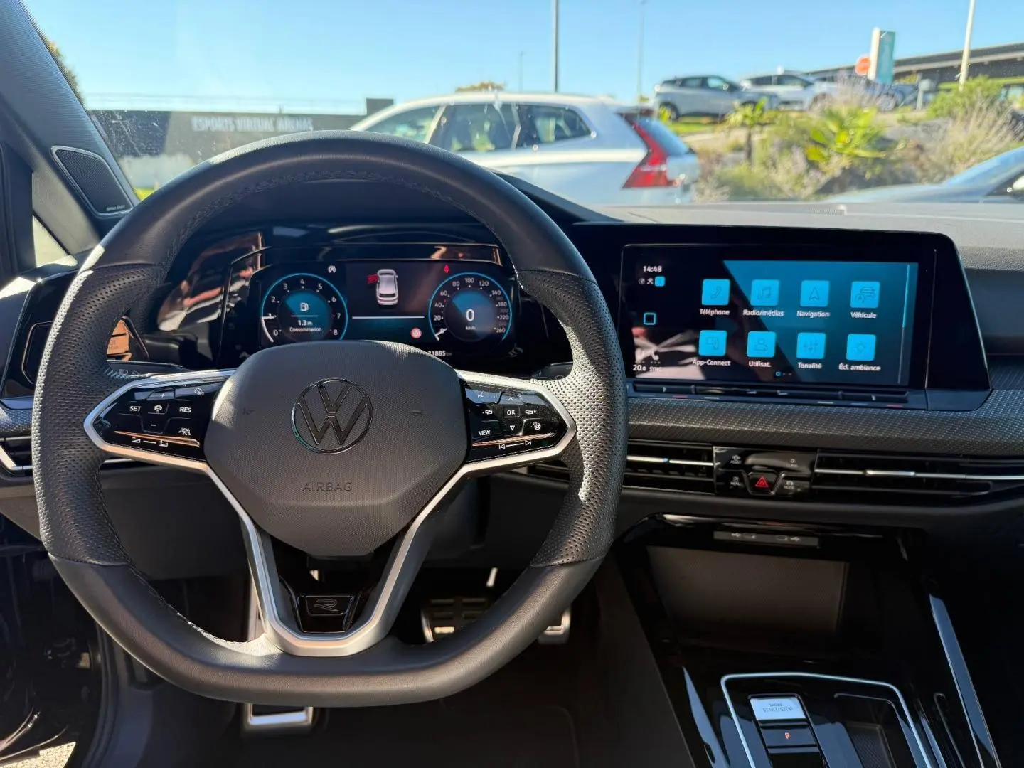 Vue intérieure centrée sur le volant cuir multifonction et l'écran tactile du tableau de bord d'une Volkswagen Golf noire.