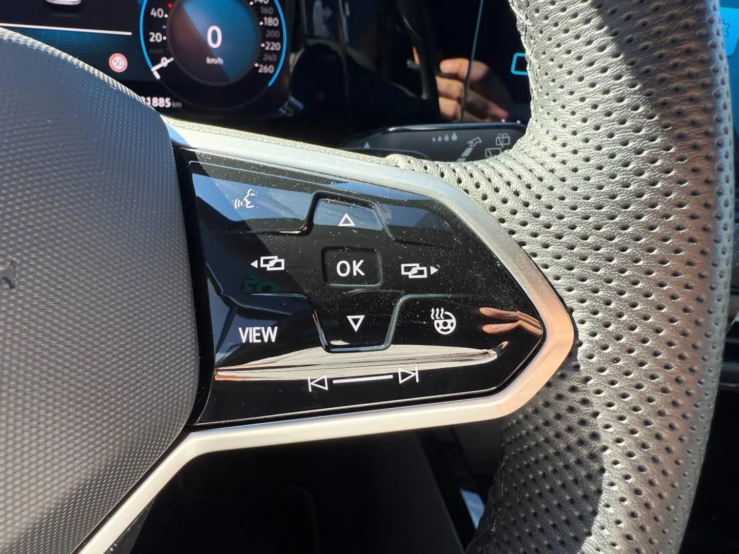 Gros plan sur les commandes noires du volant cuir perforé de la Volkswagen Golf 1.5 eTSI R-Line 2024.