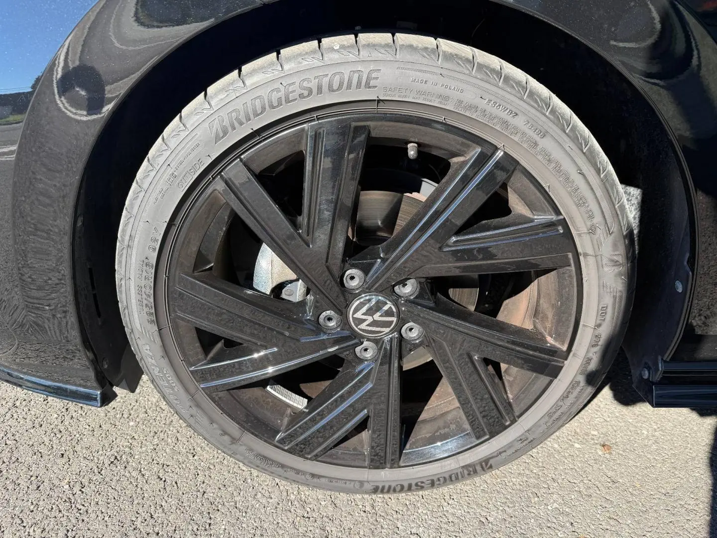 Gros plan sur la jante noire brillante de la Volkswagen Golf 2024, détail du pneu Bridgestone et logo VW central.